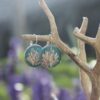 Pendientes de resina UV y acero hipoalergénico con alga coralina sobre fondo azul, hechos a mano en Malas Herbas Artesanía, artesanos gallegos.