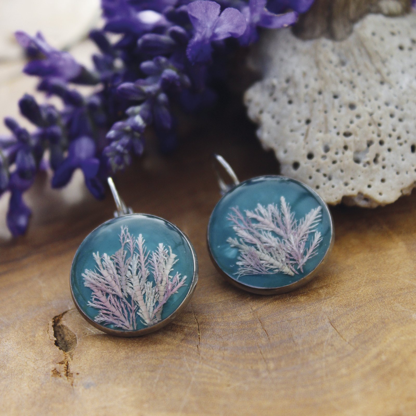 Pendientes de resina UV y acero hipoalergénico con alga coralina sobre fondo azul, hechos a mano en Malas Herbas Artesanía, artesanos gallegos.