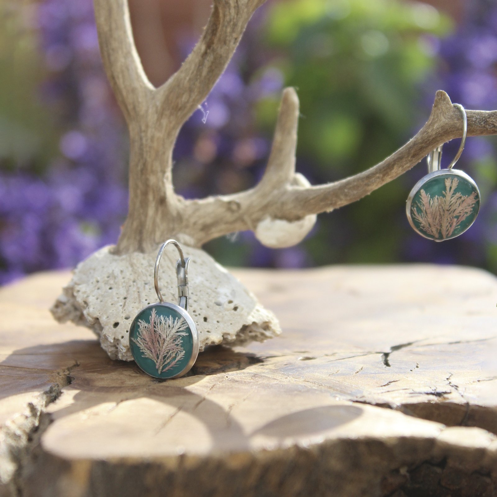 Pendientes de resina UV y acero hipoalergénico con alga coralina sobre fondo azul, hechos a mano en Malas Herbas Artesanía, artesanos gallegos.