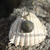 Colgante de erizo de mar natural nº 9, 17 mm, gris violáceo, con montura y cadena de latón, hecho a mano en Malas Herbas Artesanía, artesanos gallegos.