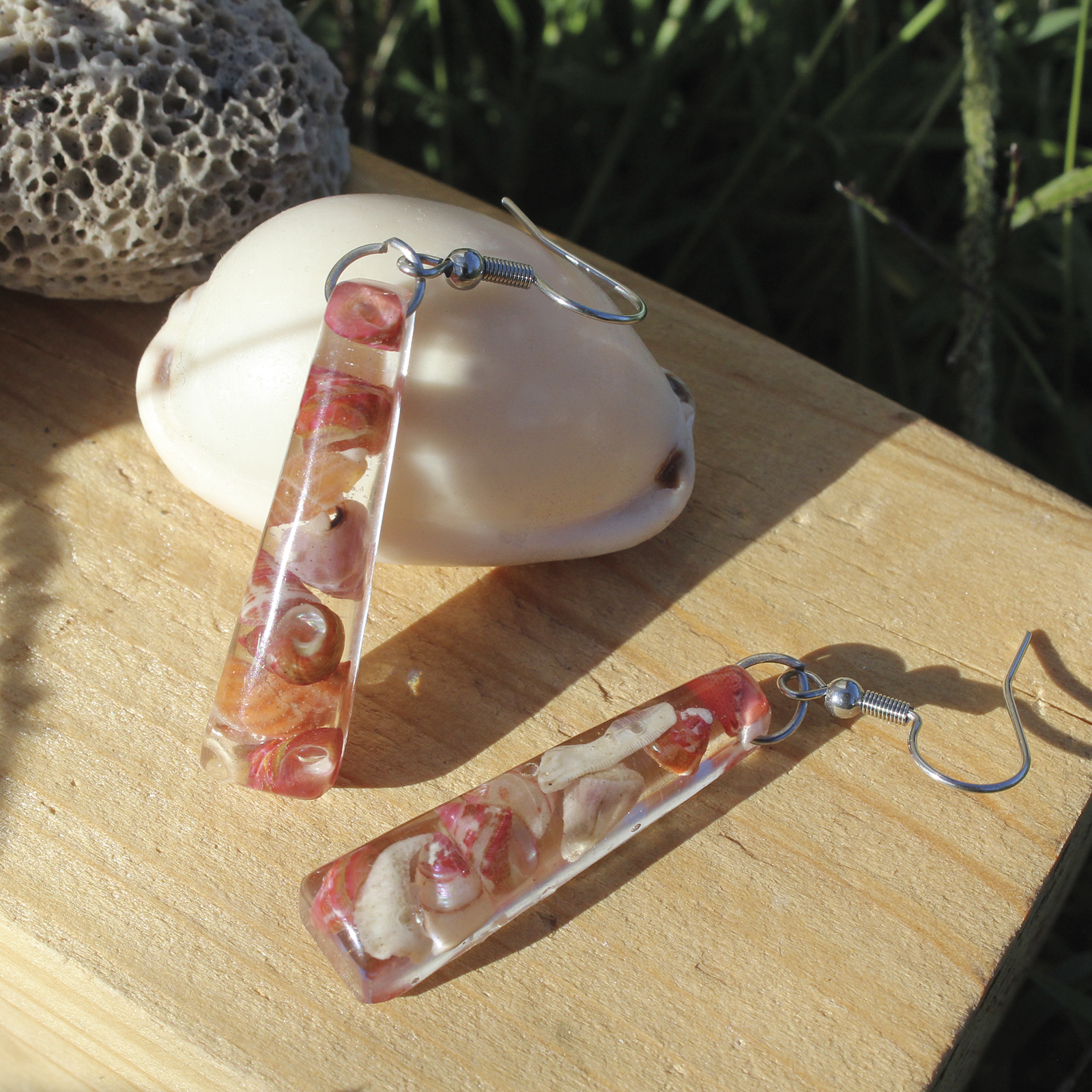 Pendientes largos de resina transparente con conchitas marinas naturales encapsuladas y ganchos de acero hipoalergénico, hechos a mano en Malas Herbas Artesanía, artesanos gallegos.