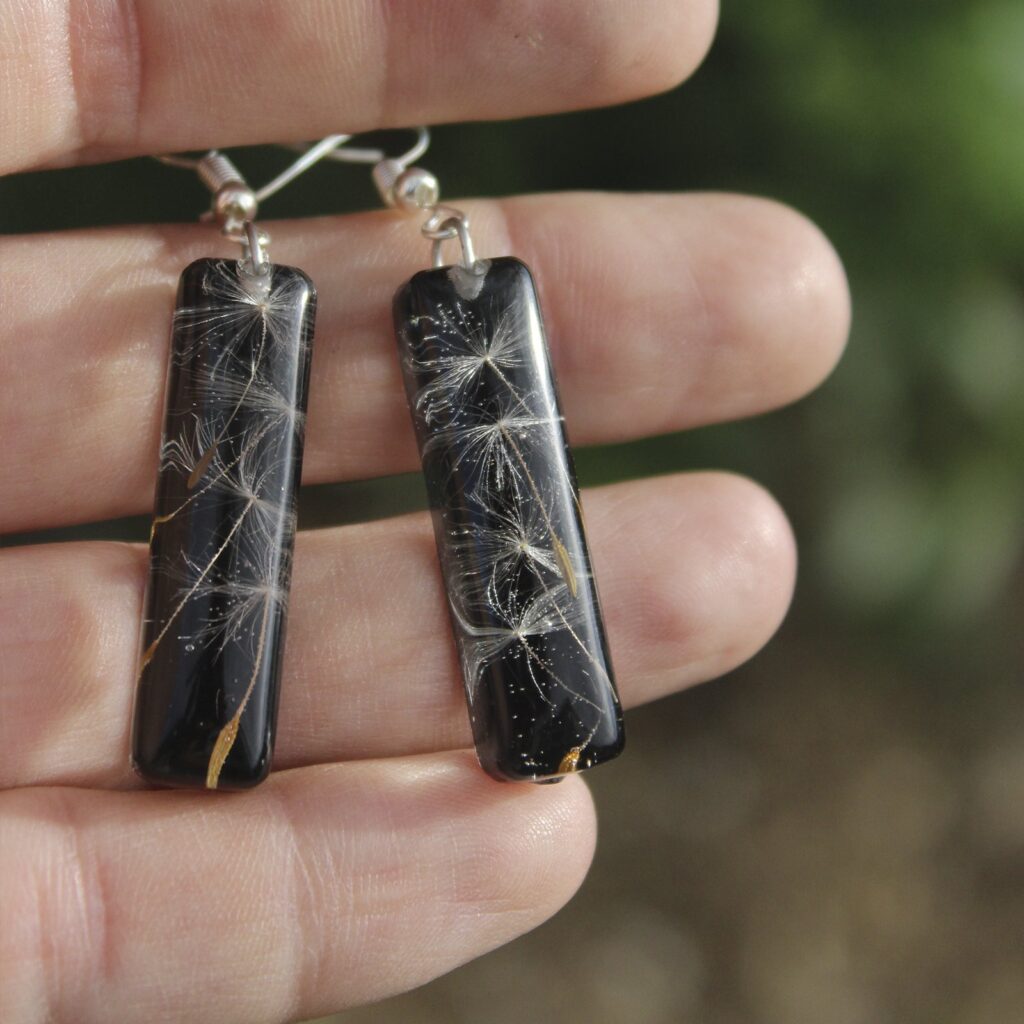 Pendientes alargados de resina UV y acero hipoalergénico con semillas de diente de león, hechos a mano en Malas Herbas Artesanía, artesanos gallegos.