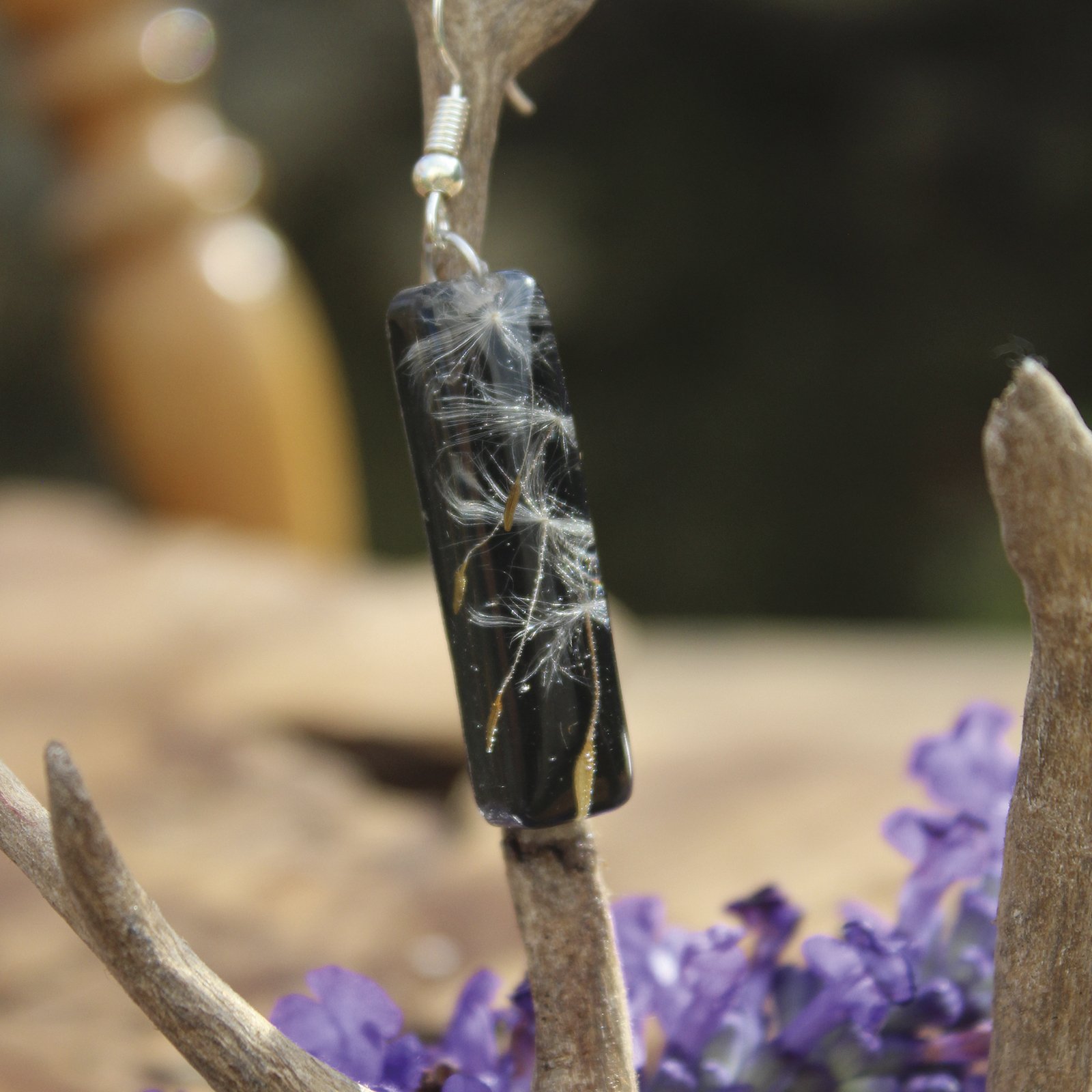 Pendientes alargados de resina UV y acero hipoalergénico con semillas de diente de león, hechos a mano en Malas Herbas Artesanía, artesanos gallegos.