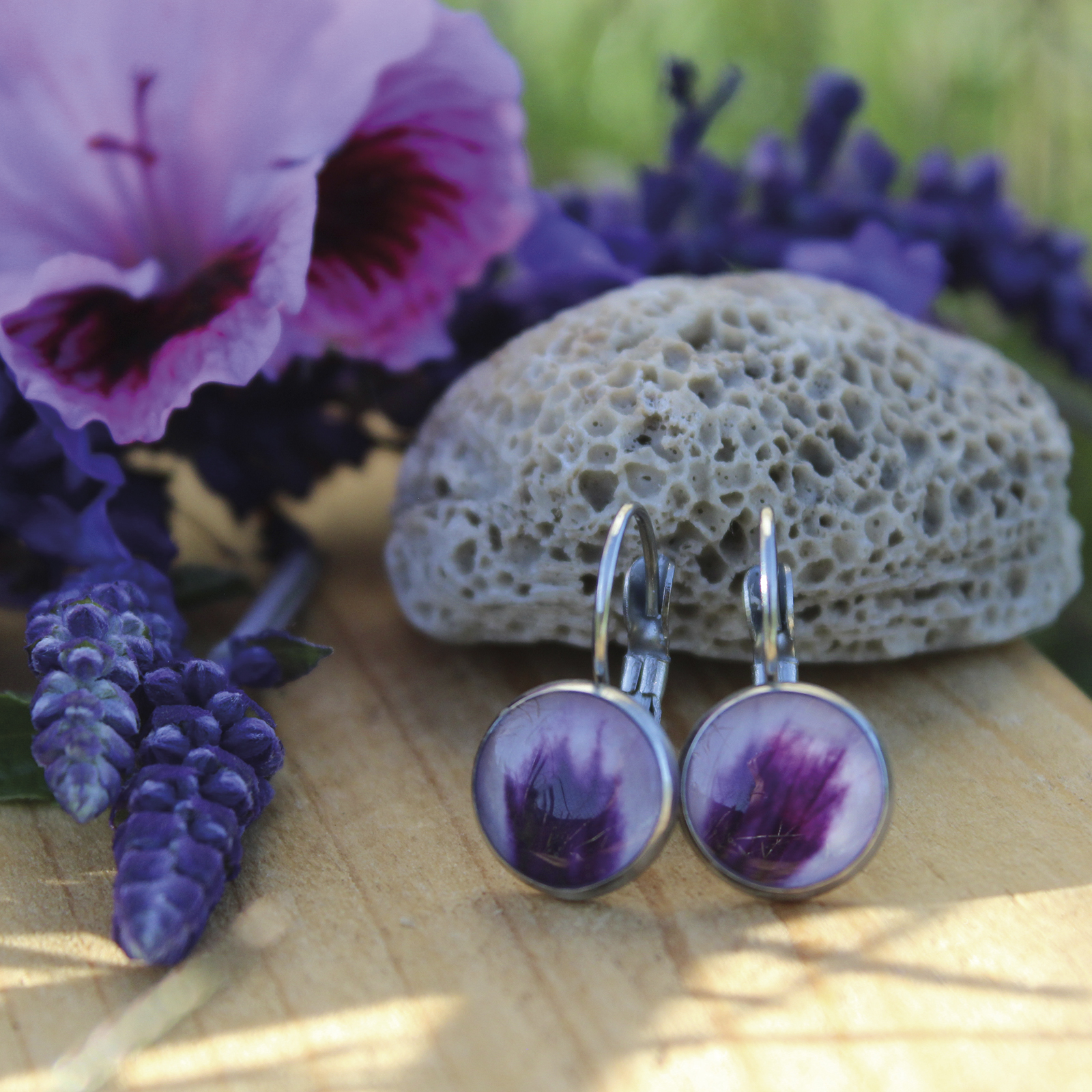 Pendientes redondos de acero hipoalergénico con pétalo de geranio natural encapsulado en resina, disponibles en cuatro tamaños, hechos a mano en Malas Herbas Artesanía, artesanos gallegos.