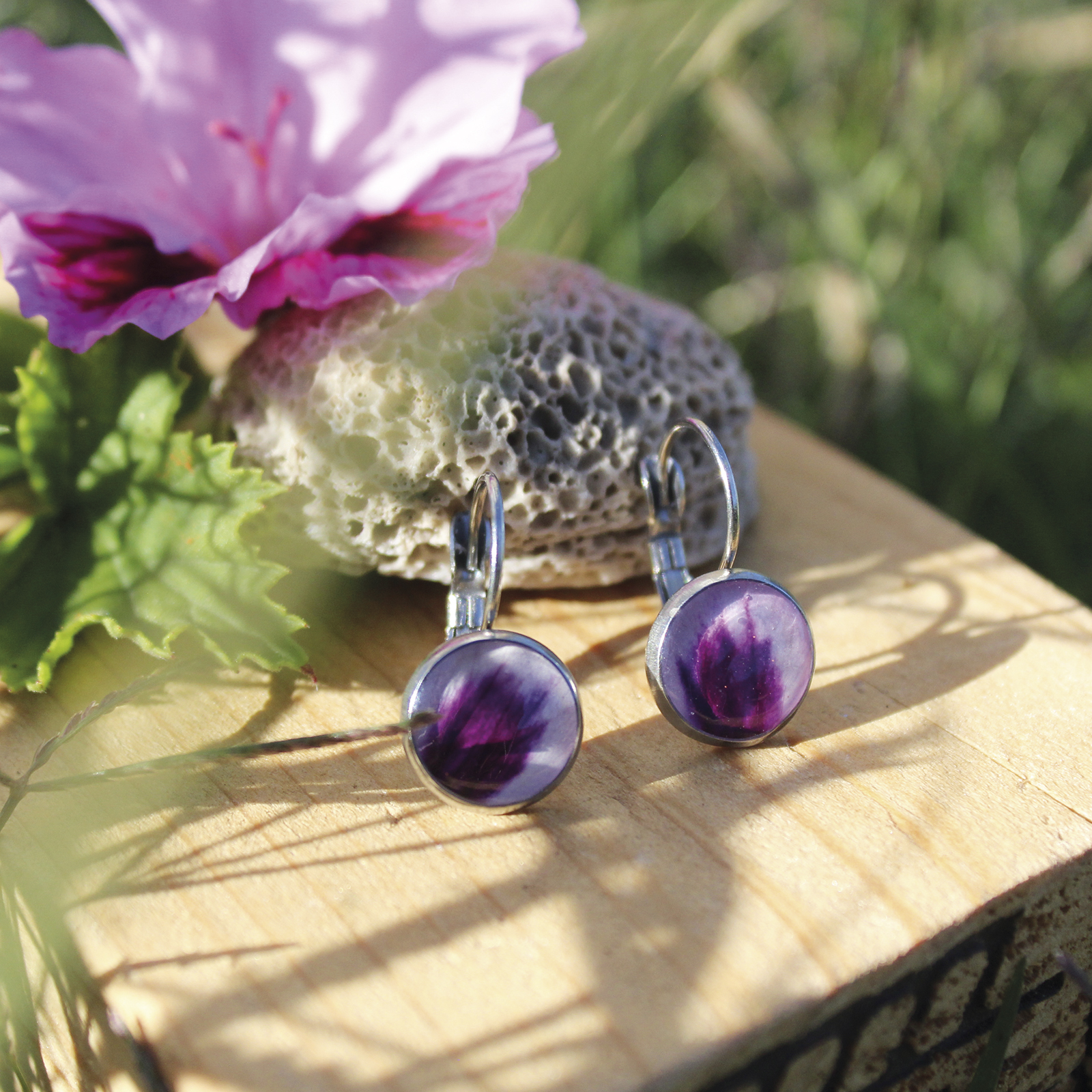 Pendientes redondos pequeños (10 mm) de acero hipoalergénico con pétalo de geranio natural en resina, hechos a mano en Malas Herbas Artesanía, artesanos gallegos.