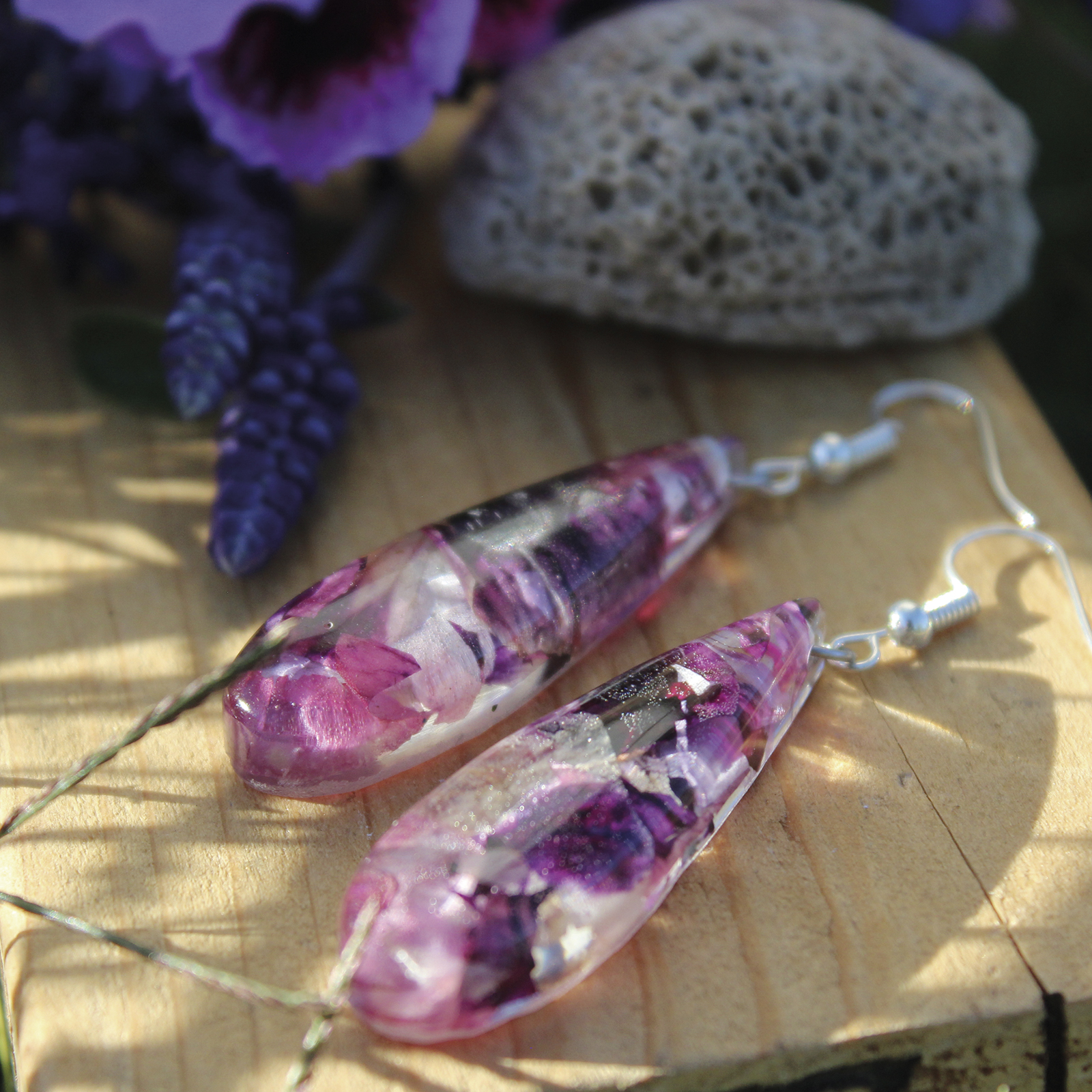 Pendientes largos en forma de gota con pétalos de geranio naturales encapsulados en resina, hechos a mano en Malas Herbas Artesanía, artesanos gallegos.
