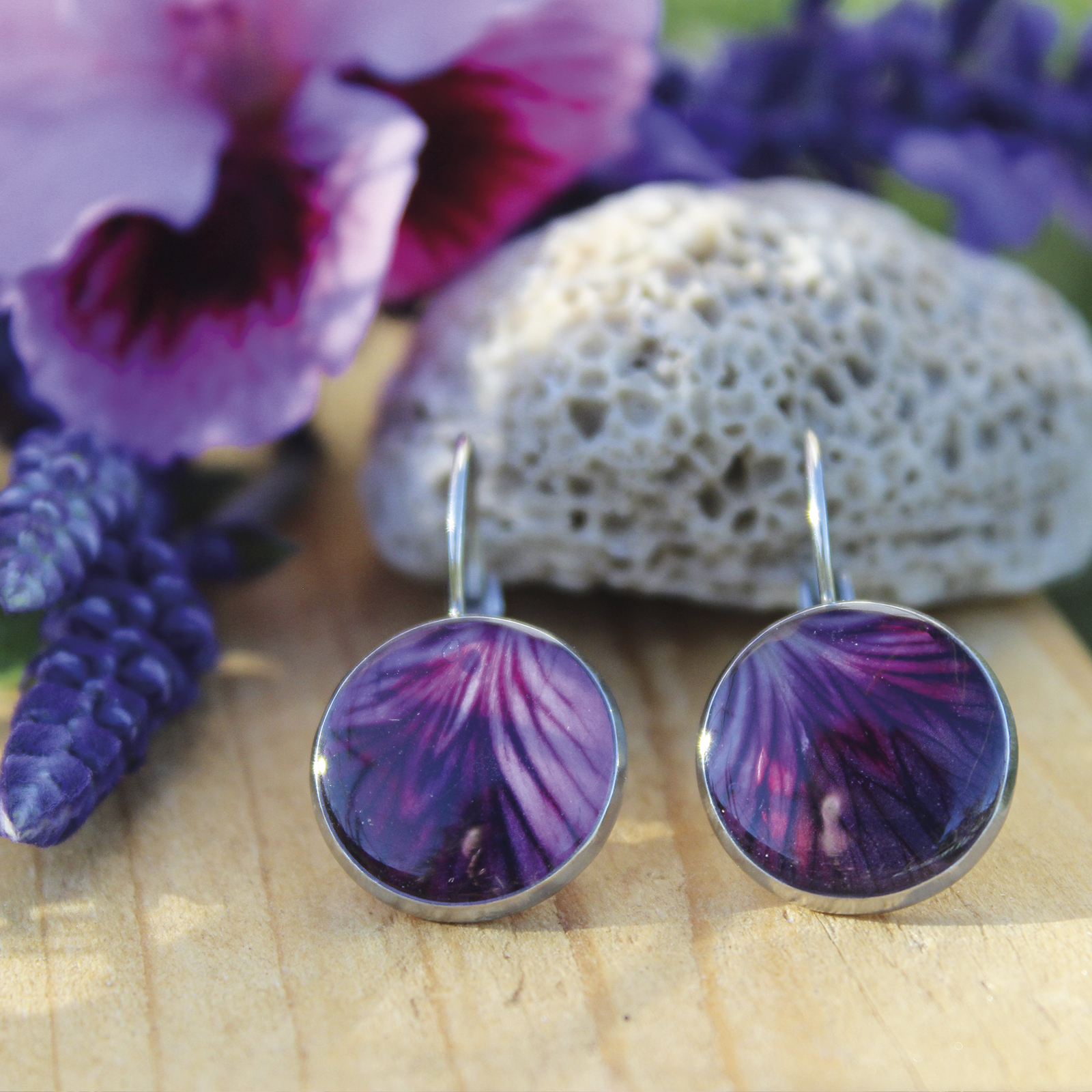 Pendientes redondos medianos (12 mm) de acero hipoalergénico con pétalo de geranio natural en resina, hechos a mano en Malas Herbas Artesanía, artesanos gallegos.