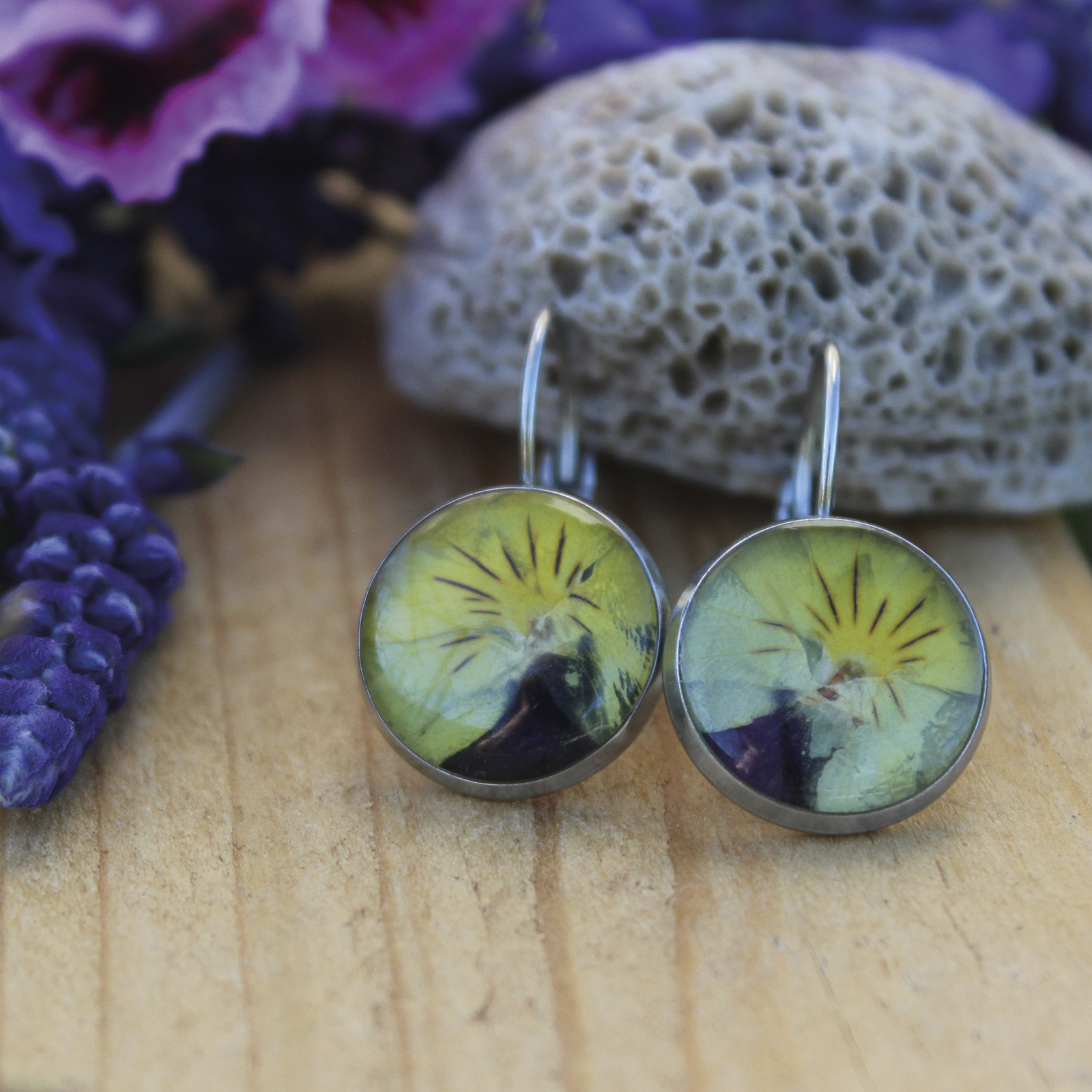 Pendientes redondos de acero hipoalergénico con flor de pensamiento amarillo natural encapsulada en resina, hechos a mano en Malas Herbas Artesanía, artesanos gallegos.