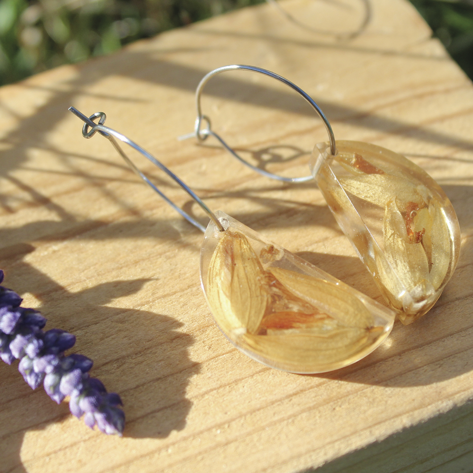 Pendientes de media luna en resina con flores de toxo naturales encapsuladas y aros de acero hipoalergénico, hechos a mano en Malas Herbas Artesanía, artesanos gallegos.