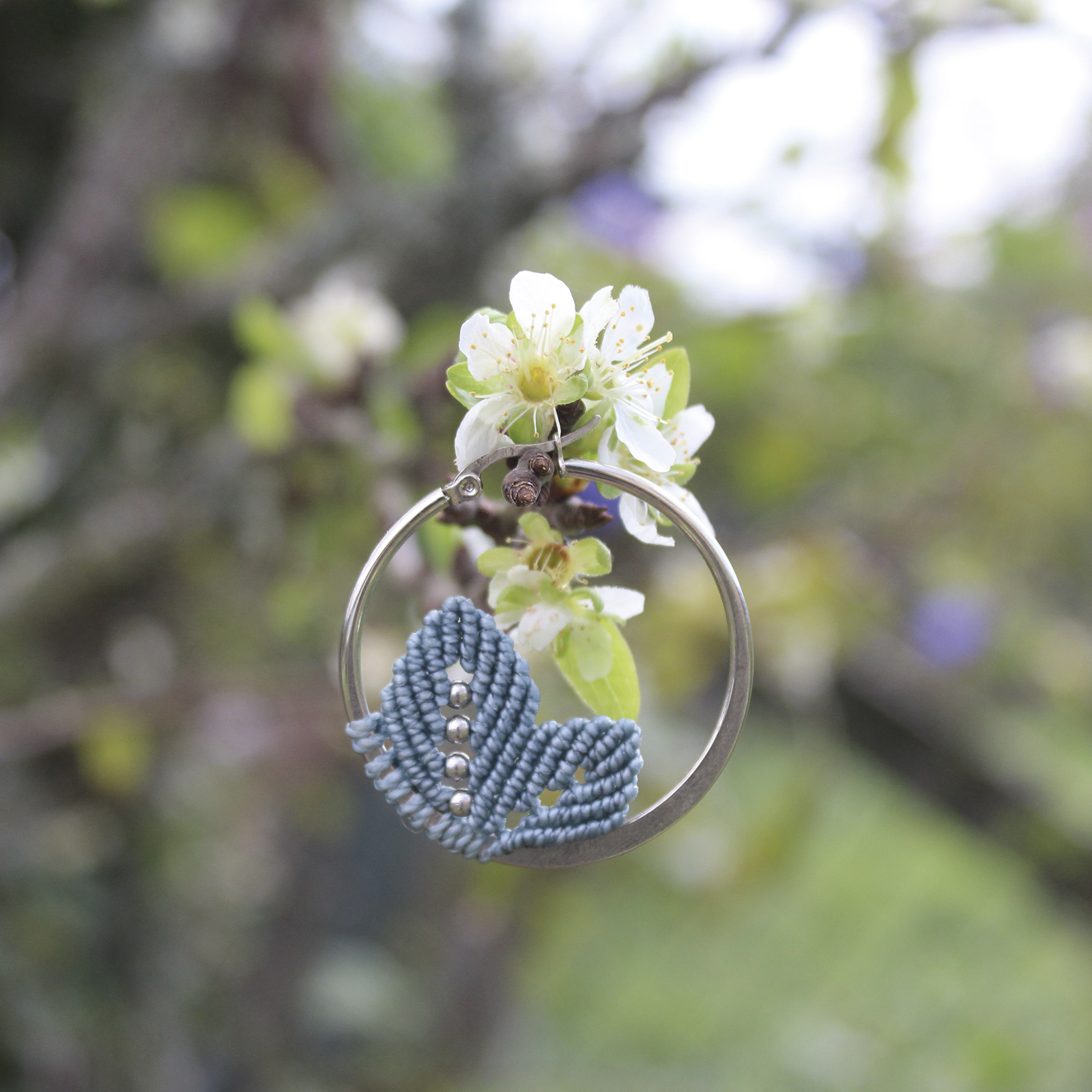 Pendientes de aro de acero plateado con hojitas de macramé en color azul, hechos a mano en Malas Herbas Artesanía, artesanos gallegos.