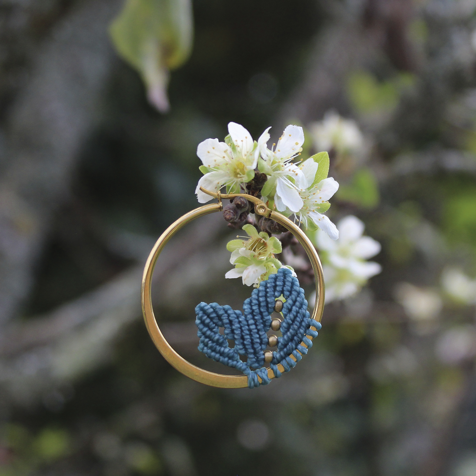 Pendientes de aro de acero dorado con hojitas de macramé en color azulón, hechos a mano en Malas Herbas Artesanía, artesanos gallegos.