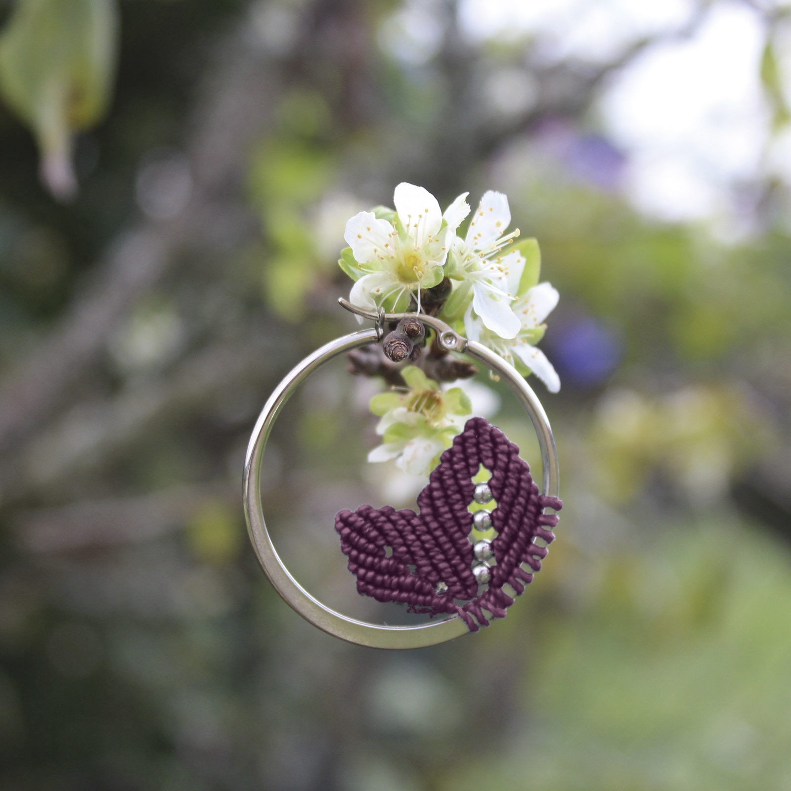 Pendientes de aro de acero plateado con hojitas de macramé en color ciruela, hechos a mano en Malas Herbas Artesanía, artesanos gallegos.