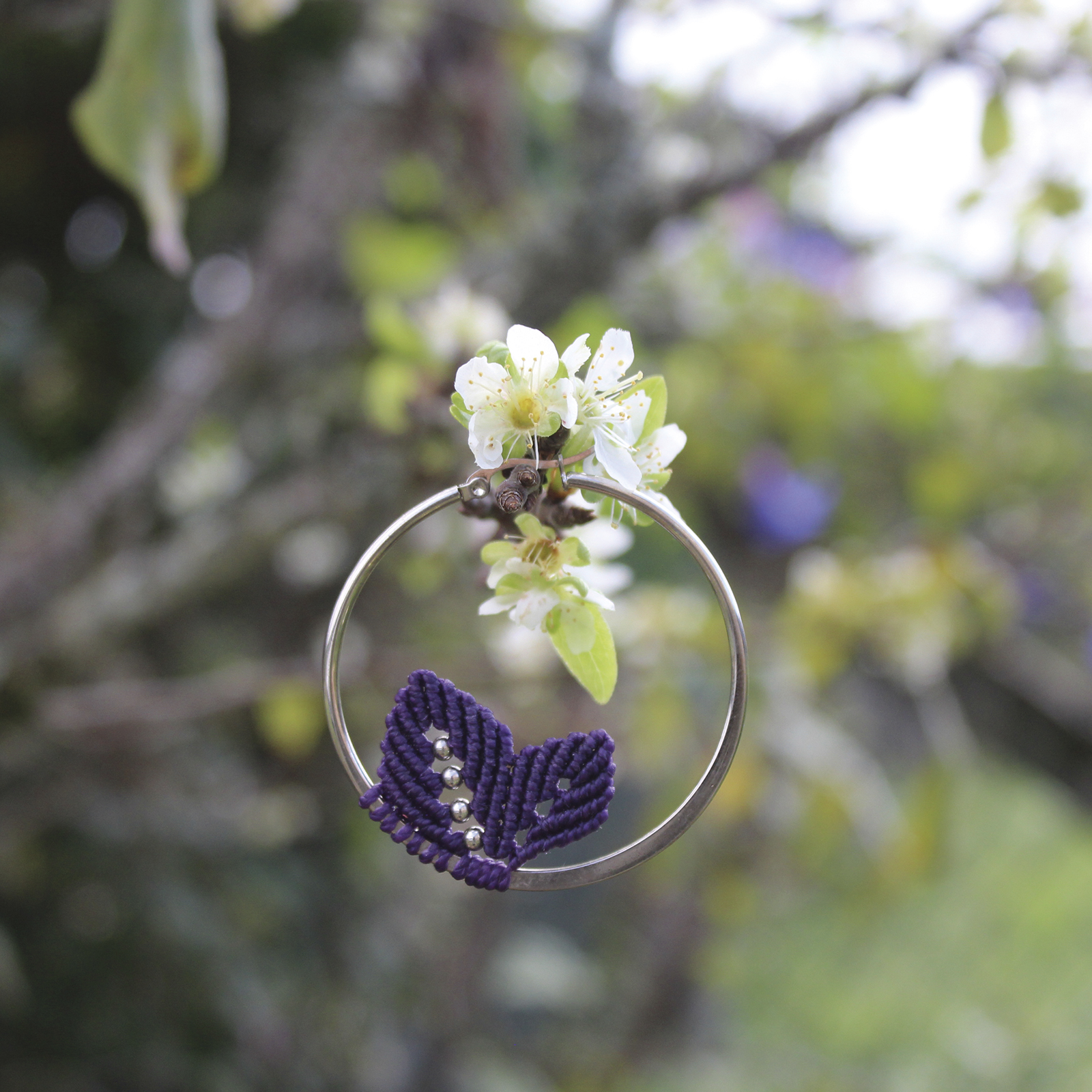 Pendientes de aro de acero plateado con hojitas de macramé en color morado, hechos a mano en Malas Herbas Artesanía, artesanos gallegos.