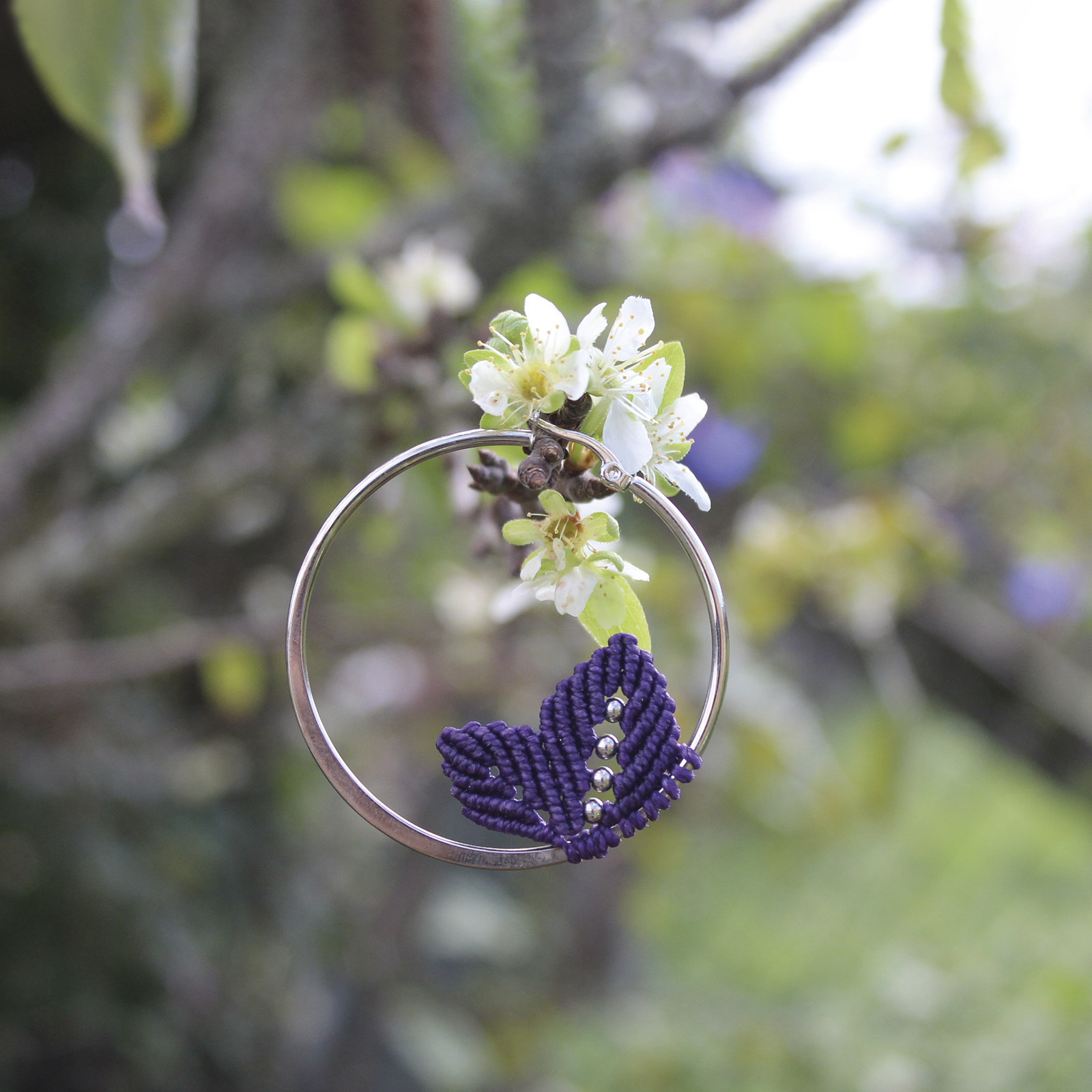 Pendientes de aro de acero plateado con hojitas de macramé en color morado, hechos a mano en Malas Herbas Artesanía, artesanos gallegos.
