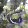 Pendientes de aro de acero plateado con hojitas de macramé en color morado, hechos a mano en Malas Herbas Artesanía, artesanos gallegos.