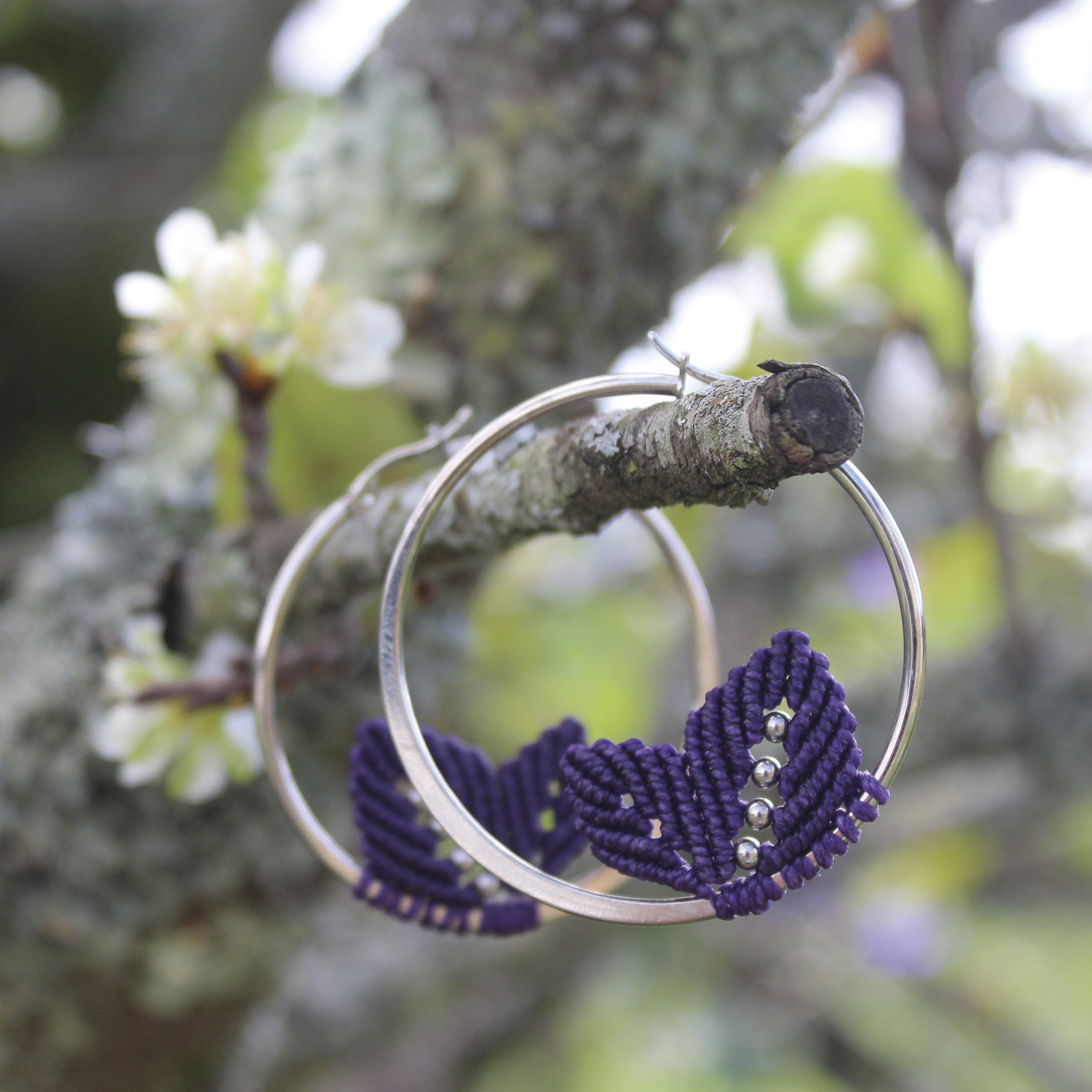 Pendientes de aro de acero plateado con hojitas de macramé en color morado, hechos a mano en Malas Herbas Artesanía, artesanos gallegos.