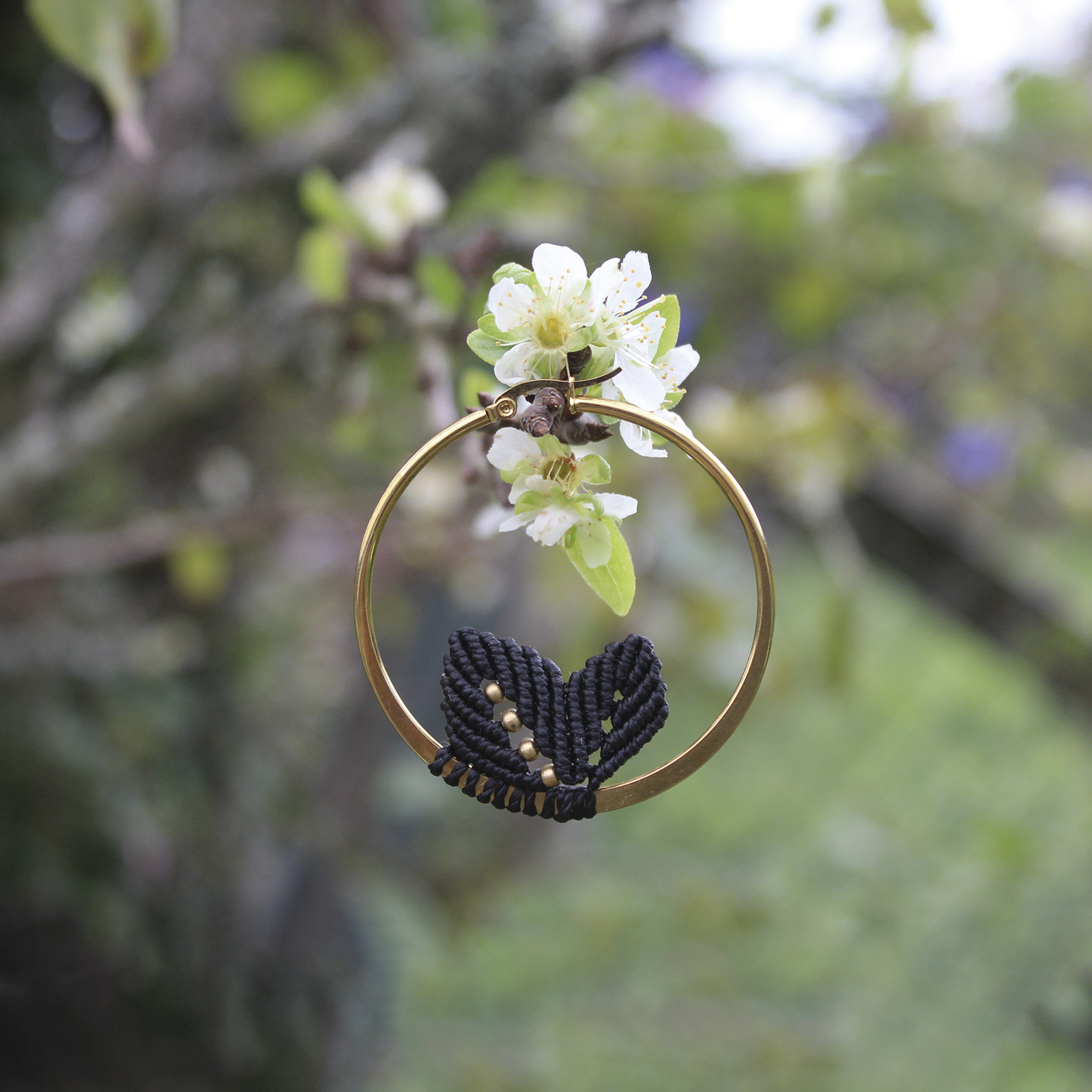 Pendientes de aro de acero dorado con hojitas de macramé en color negro, hechos a mano en Malas Herbas Artesanía, artesanos gallegos.