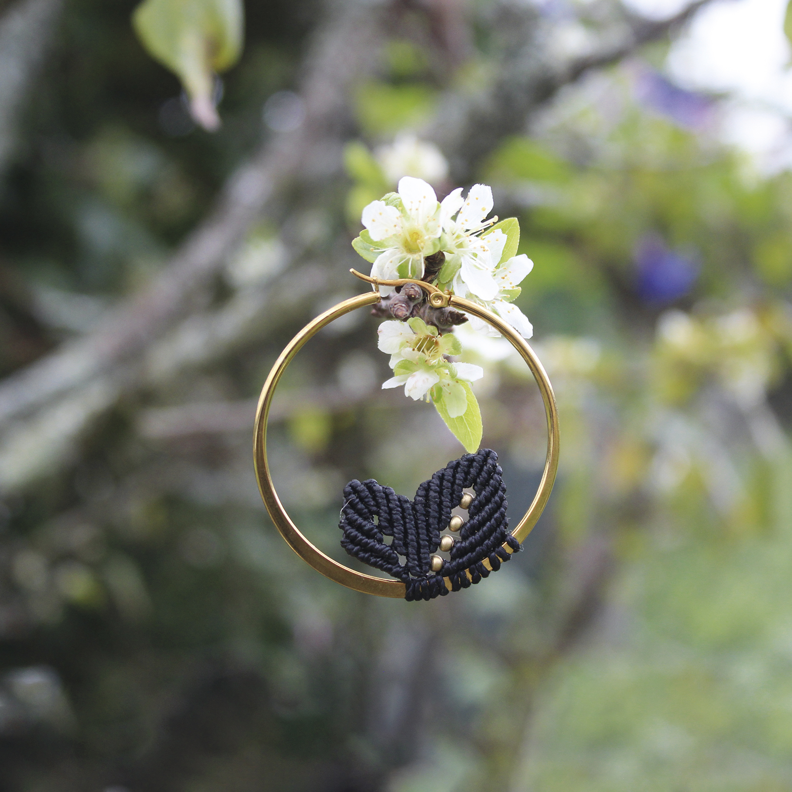 Pendientes de aro de acero dorado con hojitas de macramé en color negro, hechos a mano en Malas Herbas Artesanía, artesanos gallegos.