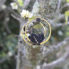 Pendientes de aro de acero dorado con hojitas de macramé en color negro, hechos a mano en Malas Herbas Artesanía, artesanos gallegos.