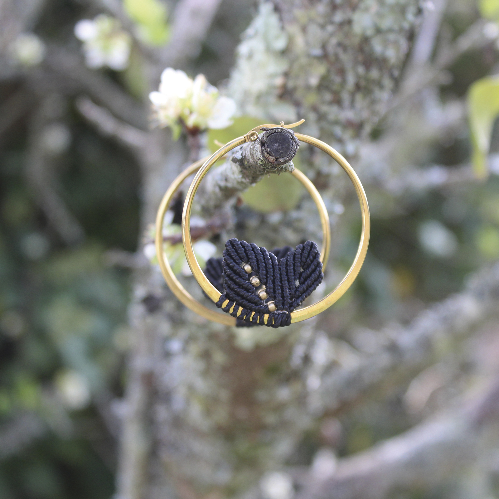 Pendientes de aro de acero dorado con hojitas de macramé en color negro, hechos a mano en Malas Herbas Artesanía, artesanos gallegos.