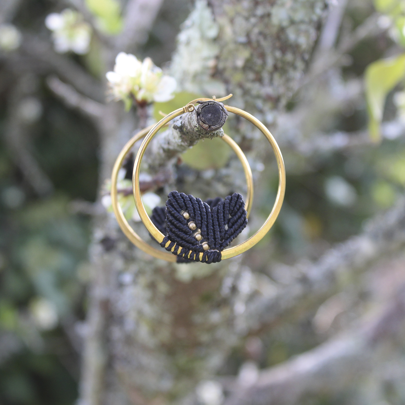 Pendientes de aro de acero dorado con hojitas de macramé en color negro, hechos a mano en Malas Herbas Artesanía, artesanos gallegos.