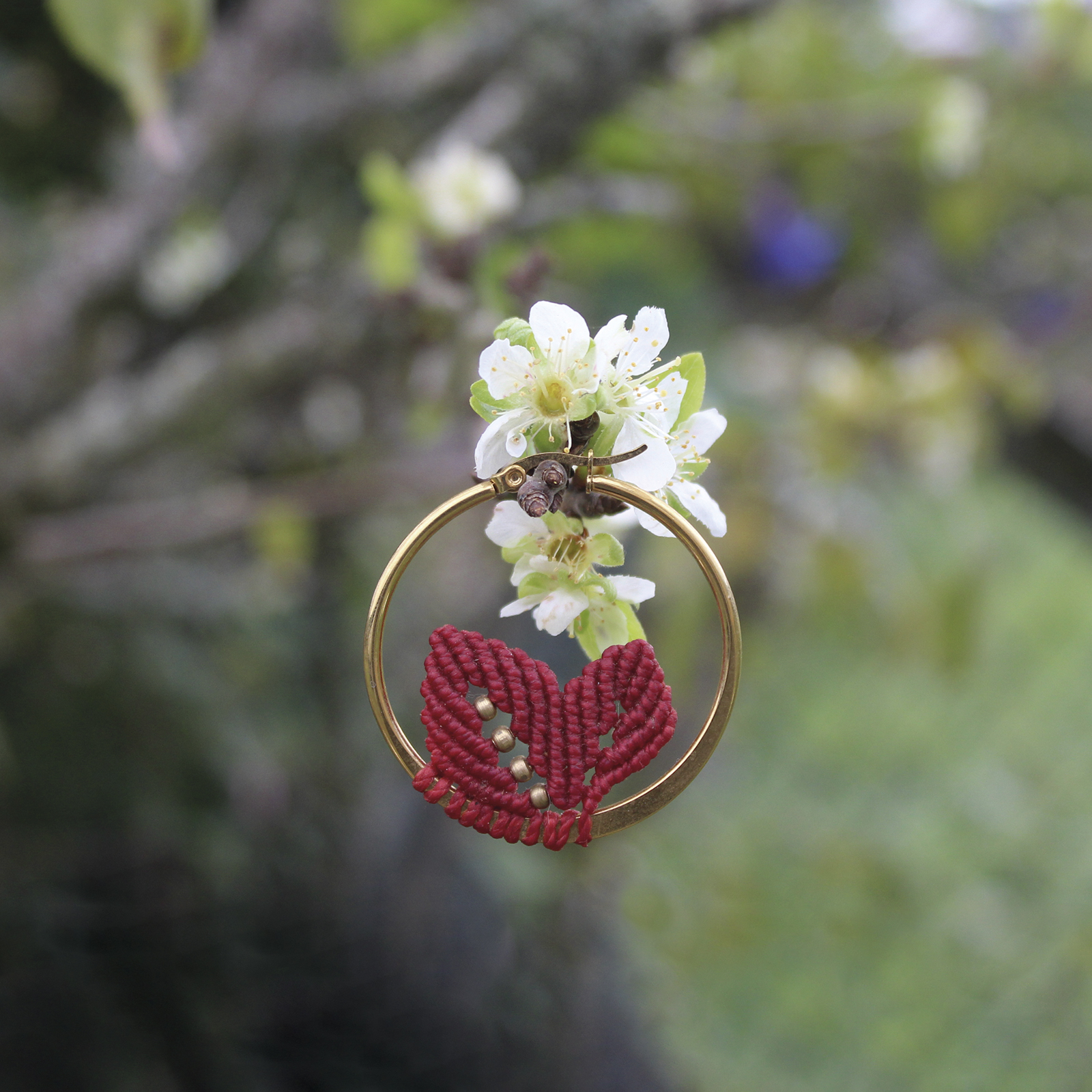 Pendientes de aro de acero dorado con hojitas de macramé en color rojo, hechos a mano en Malas Herbas Artesanía, artesanos gallegos.