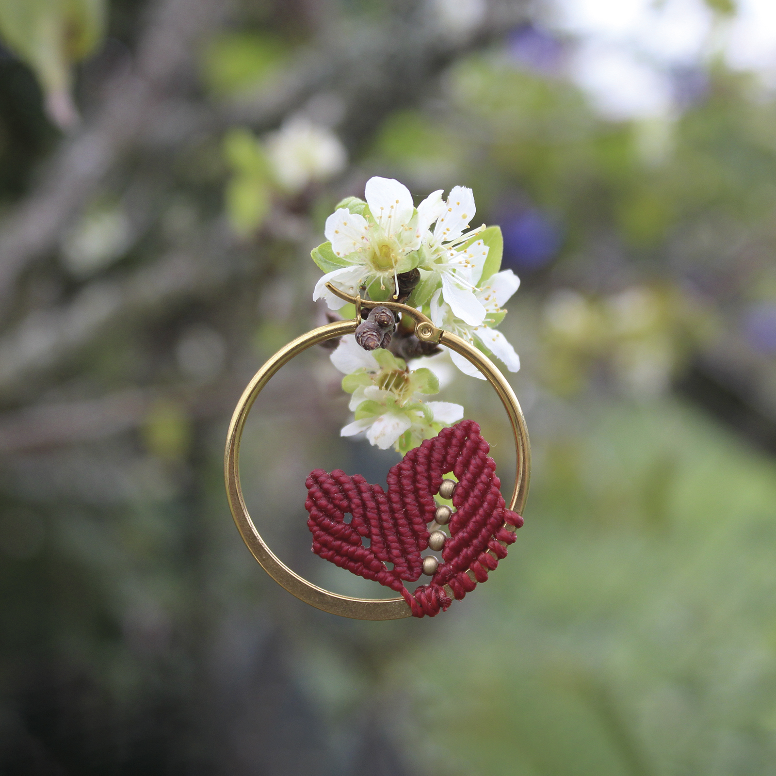 Pendientes de aro de acero dorado con hojitas de macramé en color rojo, hechos a mano en Malas Herbas Artesanía, artesanos gallegos.