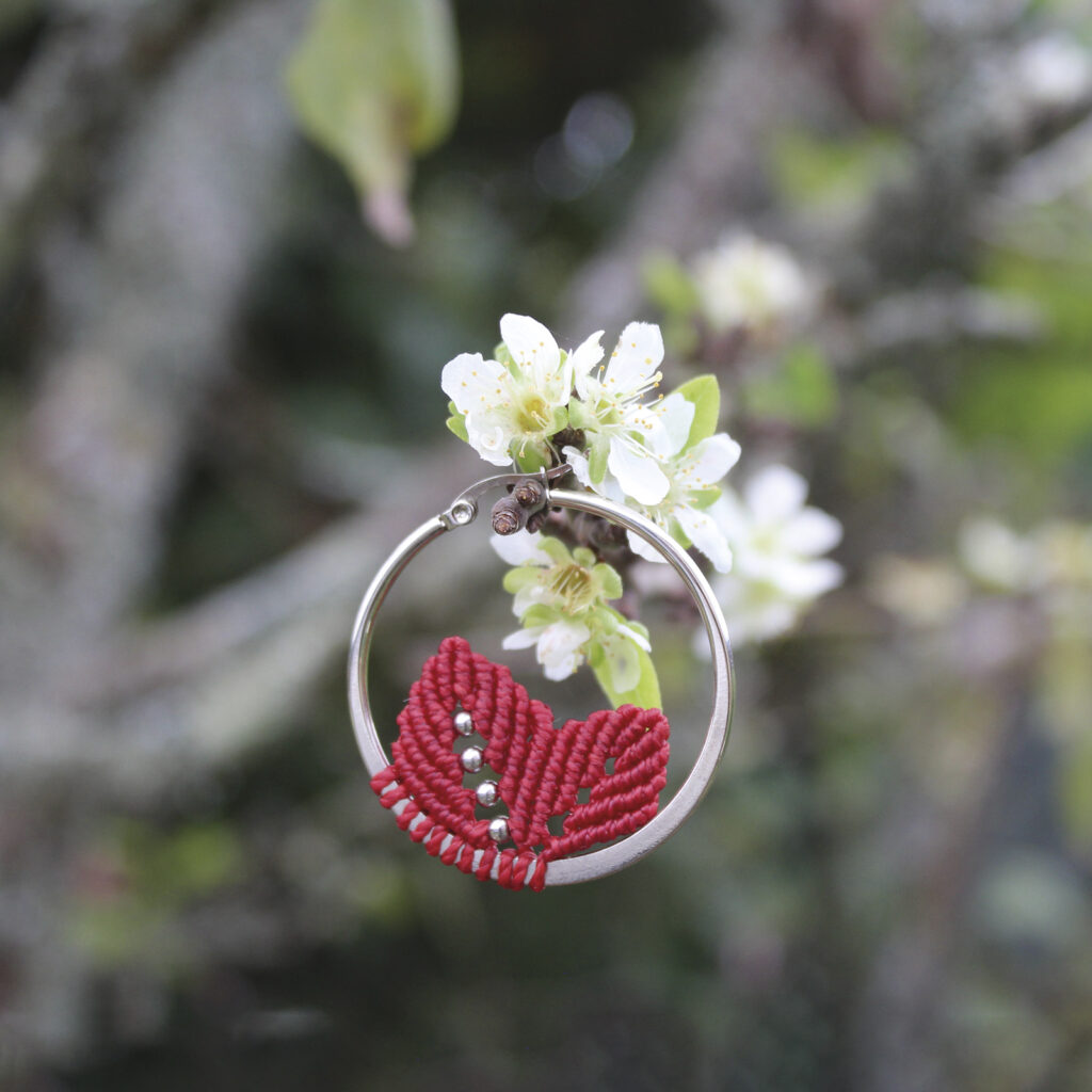 Pendientes de aro de acero plateado con hojitas de macramé en color rojo, hechos a mano en Malas Herbas Artesanía, artesanos gallegos.