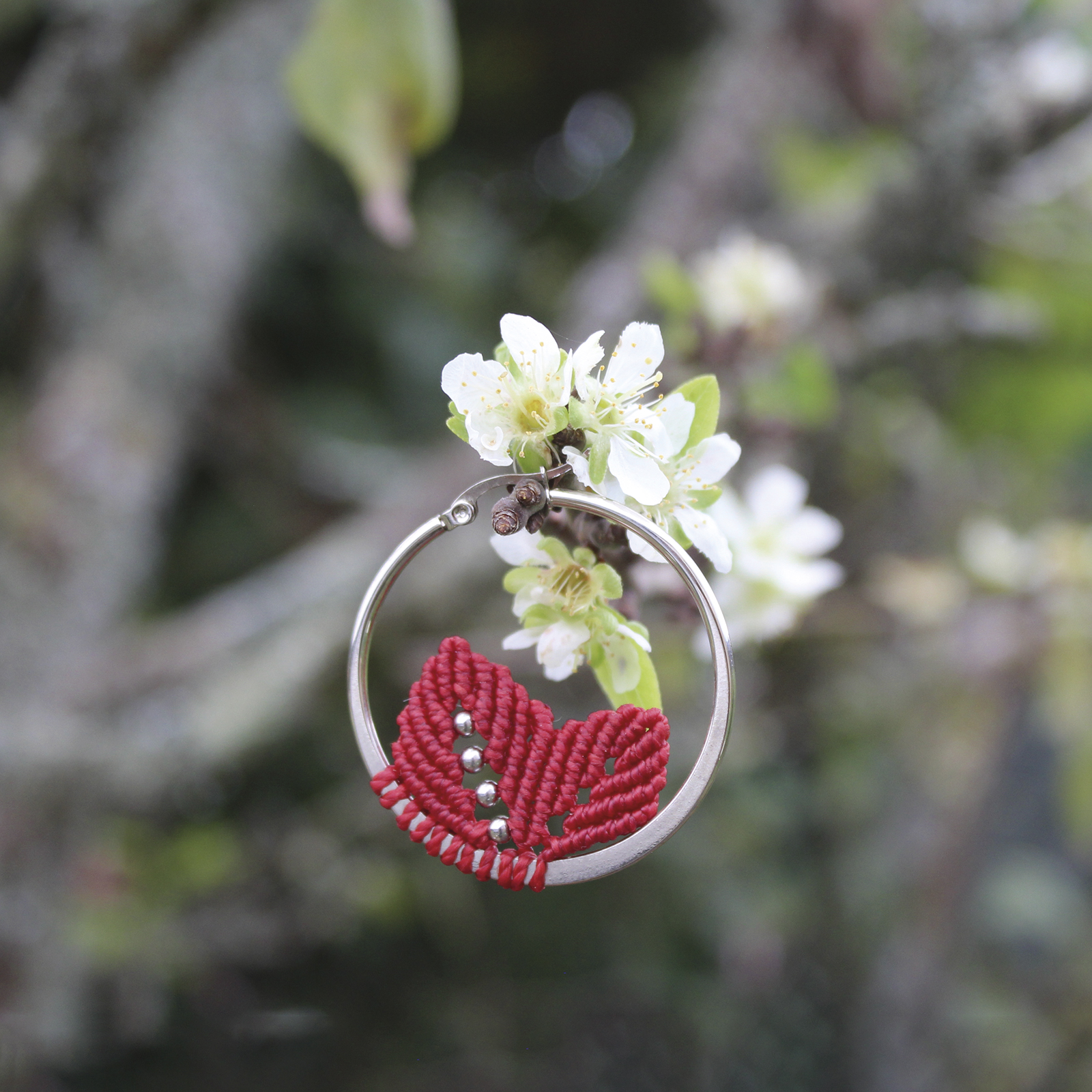 Pendientes de aro de acero plateado con hojitas de macramé en color rojo, hechos a mano en Malas Herbas Artesanía, artesanos gallegos.
