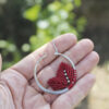 Pendientes de aro de acero plateado con hojitas de macramé en color rojo, hechos a mano en Malas Herbas Artesanía, artesanos gallegos.