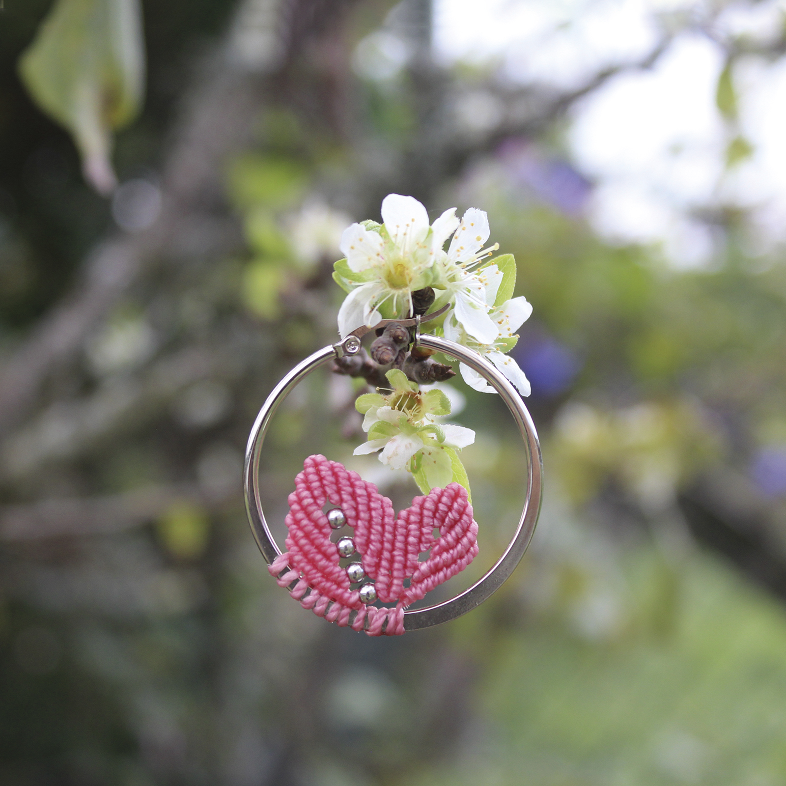Pendientes de aro de acero plateado con hojitas de macramé en color rosa, hechos a mano en Malas Herbas Artesanía, artesanos gallegos.