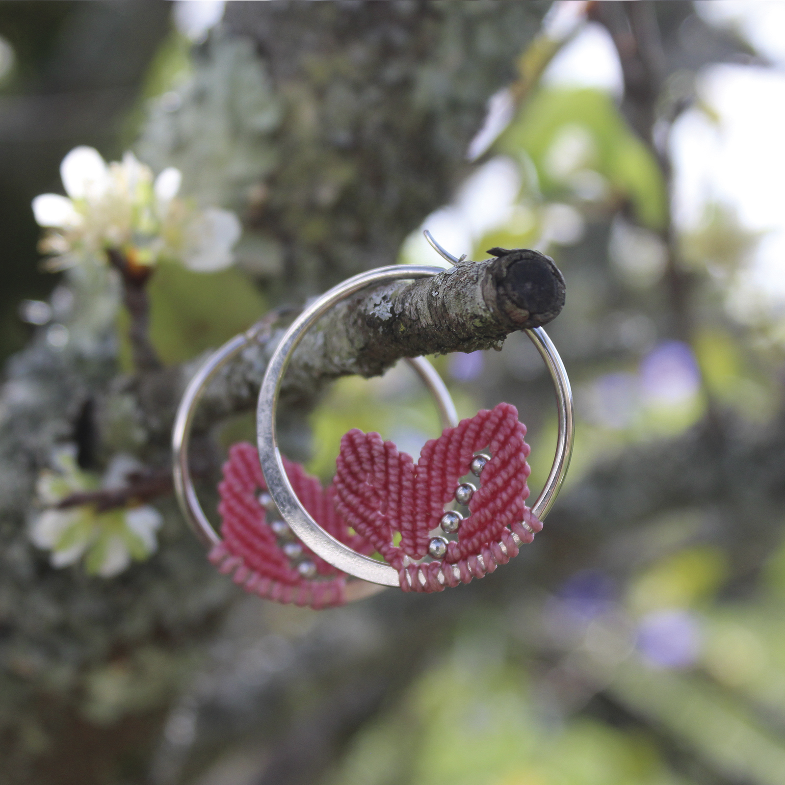 Pendientes de aro de acero plateado con hojitas de macramé en color rosa, hechos a mano en Malas Herbas Artesanía, artesanos gallegos.