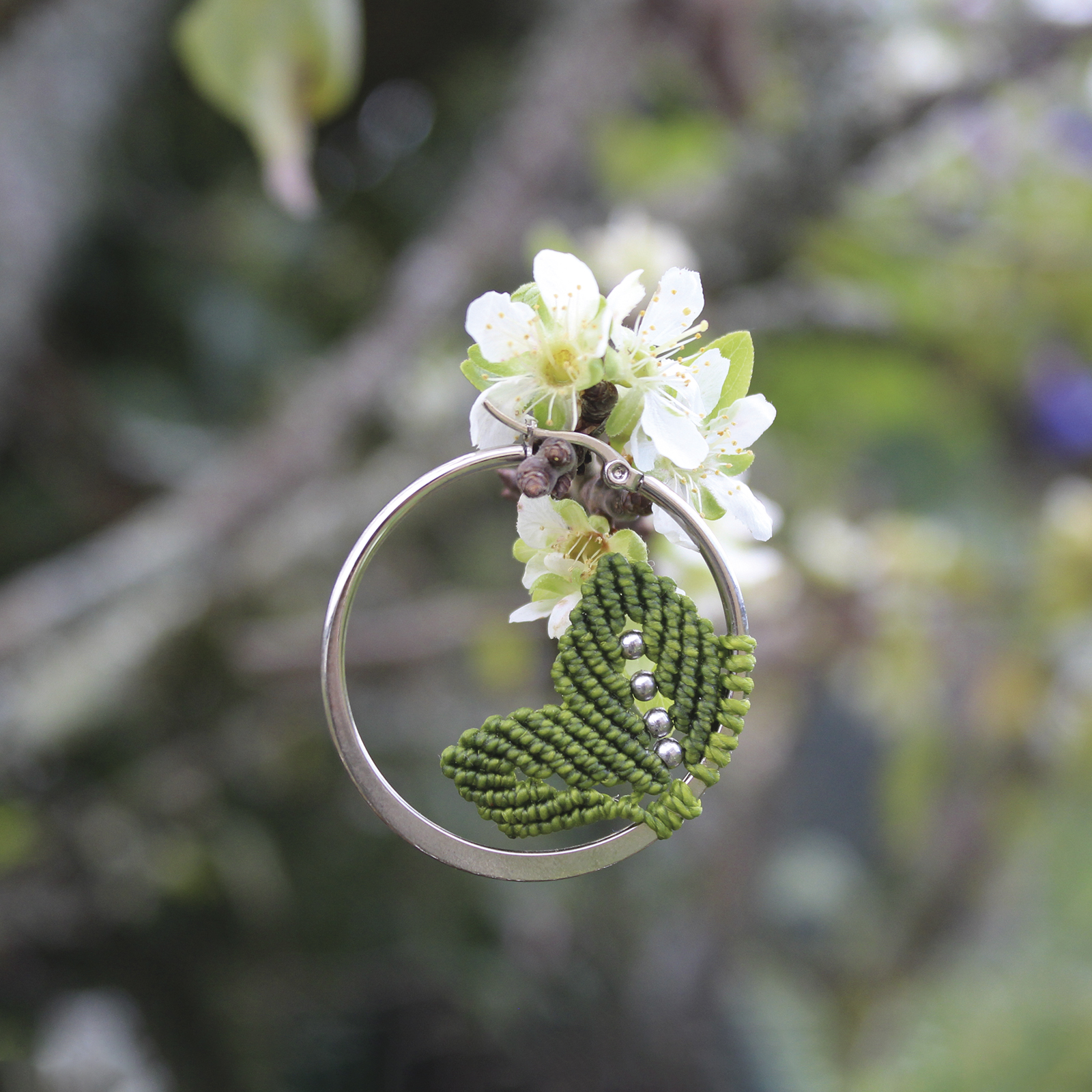Pendientes de aro de acero plateado con hojitas de macramé en color verde, hechos a mano en Malas Herbas Artesanía, artesanos gallegos.