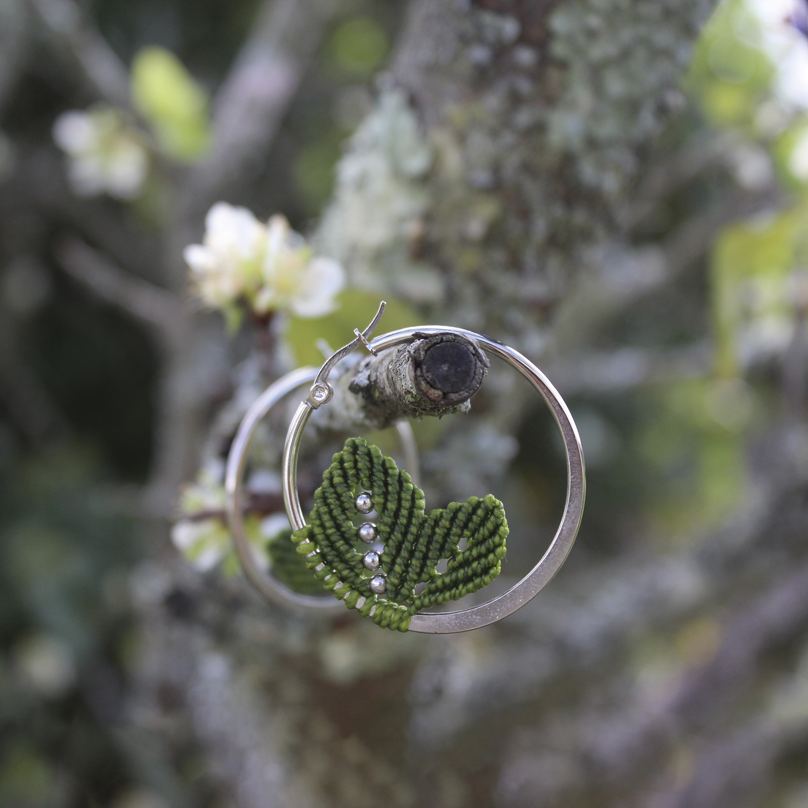 Pendientes de aro de acero plateado con hojitas de macramé en color verde, hechos a mano en Malas Herbas Artesanía, artesanos gallegos.
